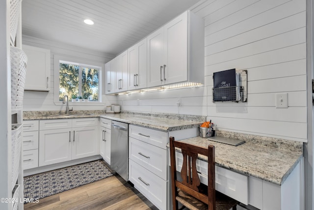 kitchen with white cabinetry, sink, stainless steel dishwasher, light hardwood / wood-style floors, and light stone countertops