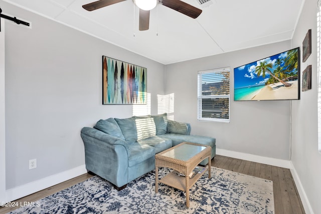 living room with ceiling fan, a barn door, and hardwood / wood-style floors