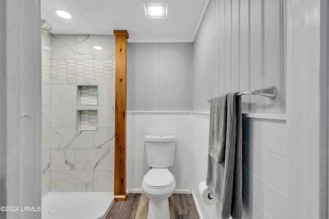 bathroom with wood-type flooring, a tile shower, and toilet