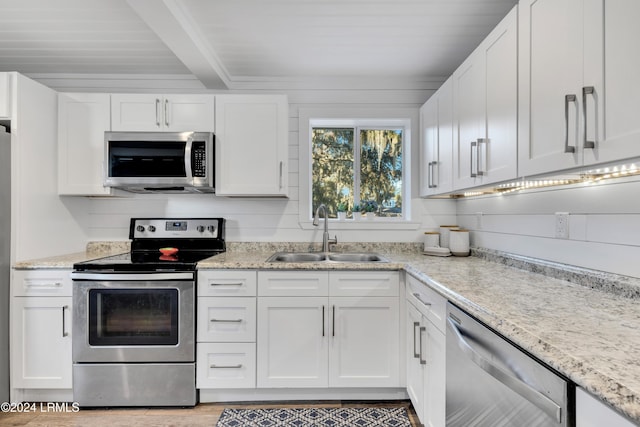 kitchen featuring sink, white cabinetry, beam ceiling, stainless steel appliances, and light stone countertops