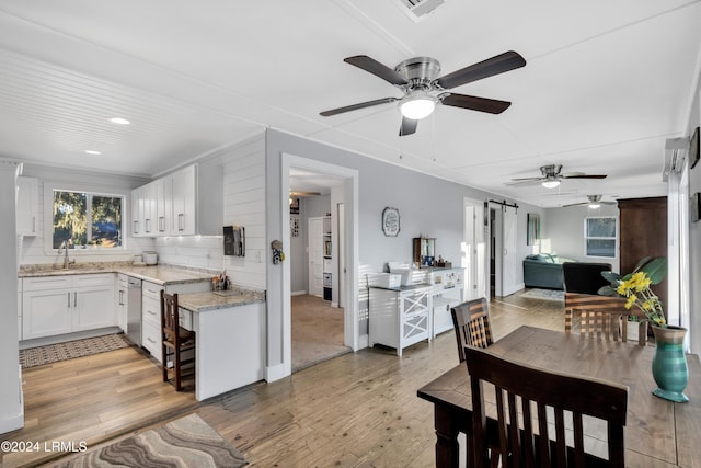 kitchen featuring sink, white cabinetry, stainless steel dishwasher, a barn door, and light hardwood / wood-style floors