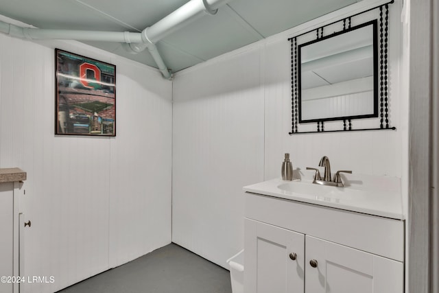 bathroom featuring concrete flooring, vanity, and wood walls