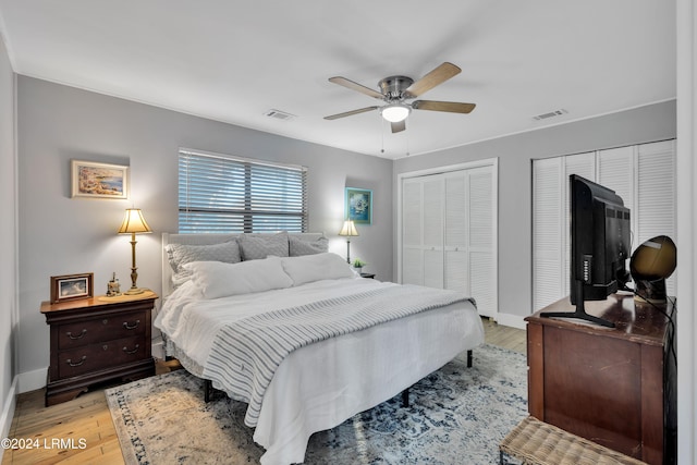 bedroom featuring multiple closets, light hardwood / wood-style floors, and ceiling fan