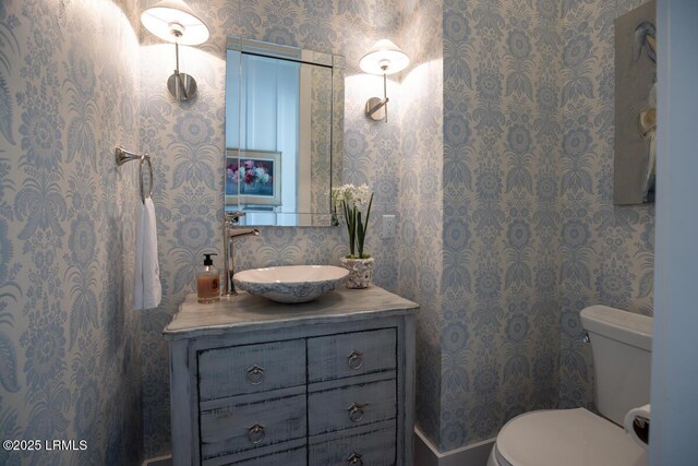 bathroom featuring vanity, toilet, and wallpapered walls