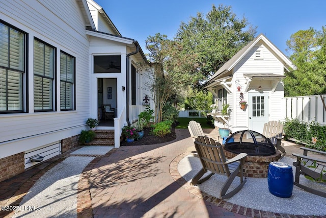 view of patio / terrace with an outdoor fire pit, fence, and an outbuilding