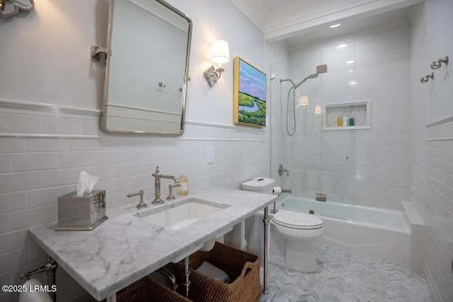 full bath featuring shower / bath combination, toilet, a wainscoted wall, a sink, and tile walls