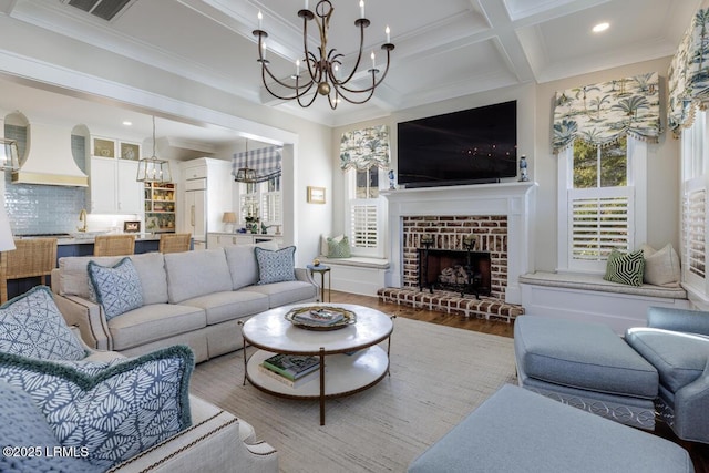 living room with a fireplace, wood finished floors, visible vents, and crown molding