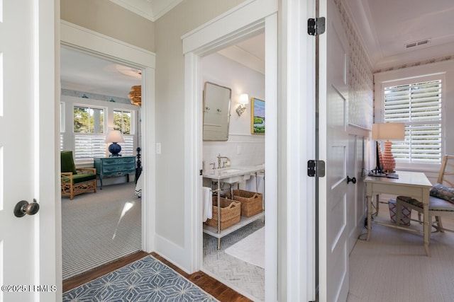 hallway featuring visible vents, crown molding, and wood finished floors