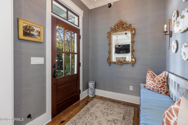 foyer with wallpapered walls, visible vents, baseboards, and wood finished floors