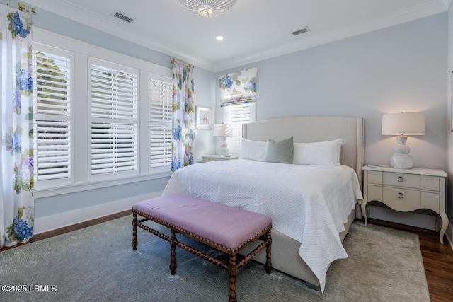 bedroom with ornamental molding, visible vents, baseboards, and wood finished floors