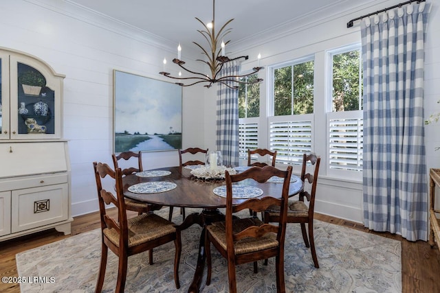 dining space with an inviting chandelier, ornamental molding, and wood finished floors