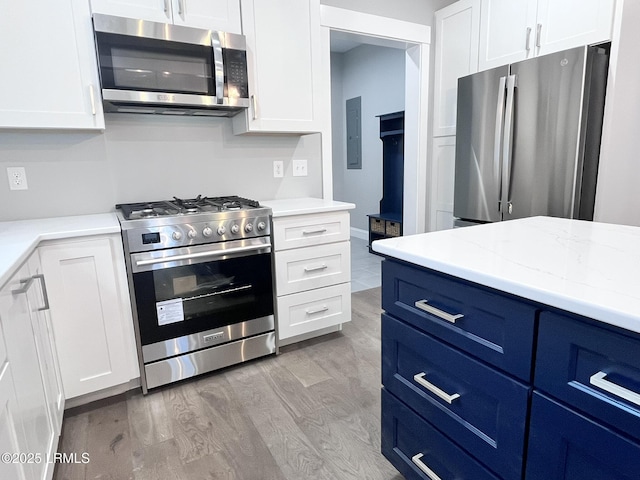 9 Attaway Ln, Beaufort, SC 29907 - kitchen featuring appliances with stainless steel finishes, blue cabinets, light wood-type flooring, white cabinets, and light stone countertops