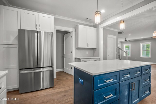 9 Attaway Ln, Beaufort, SC 29907 - kitchen with freestanding refrigerator, blue cabinetry, ornamental molding, white cabinetry, and wood finished floors
