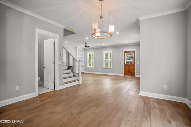 9 Attaway Ln, Beaufort, SC 29907 - unfurnished living room featuring stairs, wood finished floors, crown molding, a chandelier, and baseboards