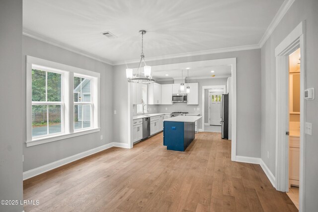 9 Attaway Ln, Beaufort, SC 29907 - kitchen with appliances with stainless steel finishes, light countertops, white cabinetry, light wood-style floors, and ornamental molding