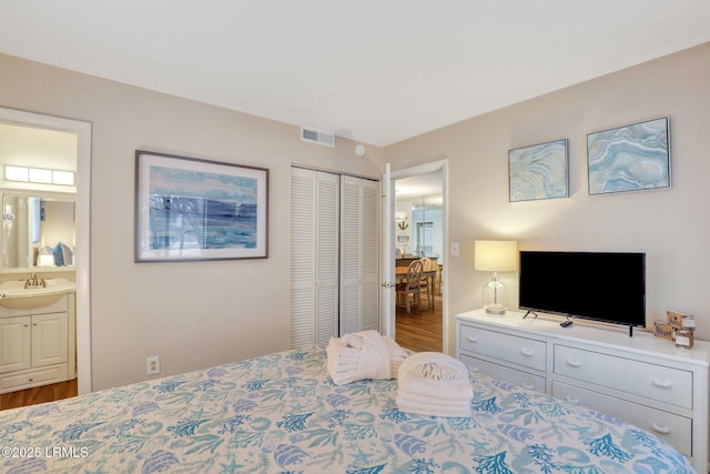 bedroom featuring sink, hardwood / wood-style flooring, a closet, and ensuite bathroom