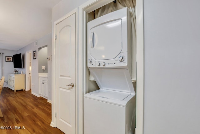 laundry area with stacked washer and clothes dryer and dark hardwood / wood-style floors