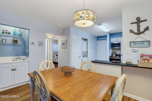 dining room featuring stacked washer and dryer, hardwood / wood-style floors, and wet bar