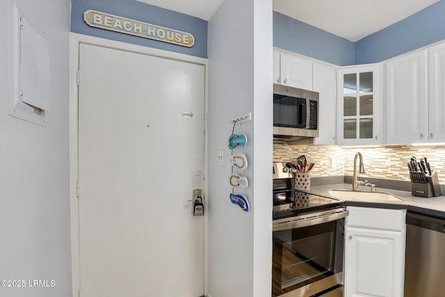 kitchen with stainless steel appliances, sink, decorative backsplash, and white cabinets