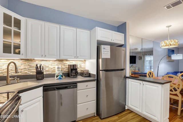 kitchen with stainless steel appliances, hanging light fixtures, white cabinets, and decorative backsplash