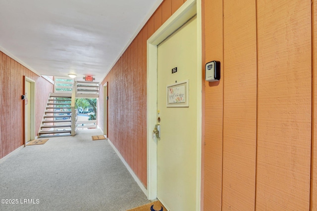 corridor with crown molding, carpet floors, and wood walls