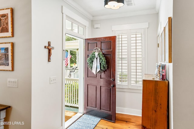 foyer entrance with visible vents, ornamental molding, a wealth of natural light, and wood finished floors
