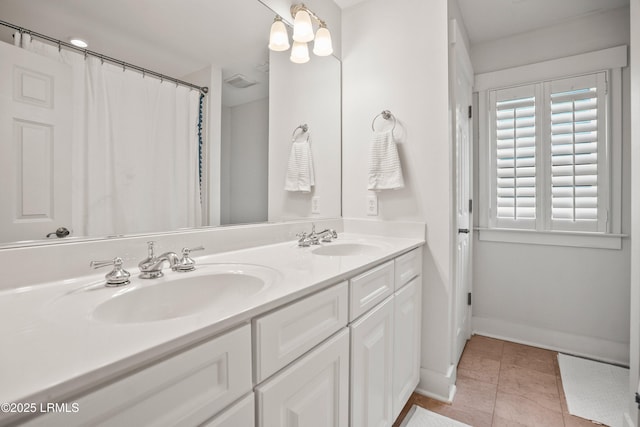 bathroom with double vanity, baseboards, visible vents, and a sink