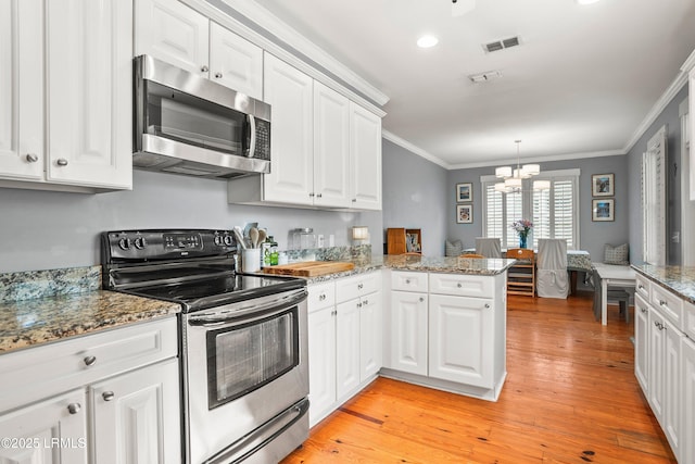 kitchen with ornamental molding, stainless steel appliances, white cabinets, and visible vents