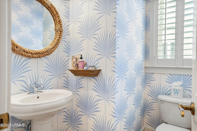 half bath with toilet and wallpapered walls