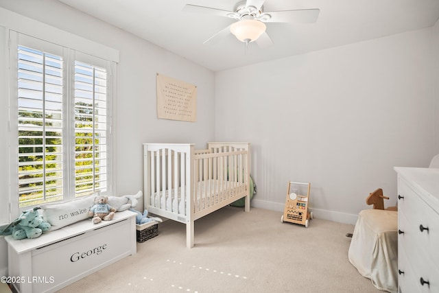 bedroom with carpet floors, a crib, ceiling fan, and multiple windows