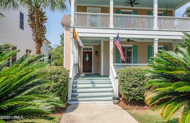 view of exterior entry featuring ceiling fan, a porch, and a balcony