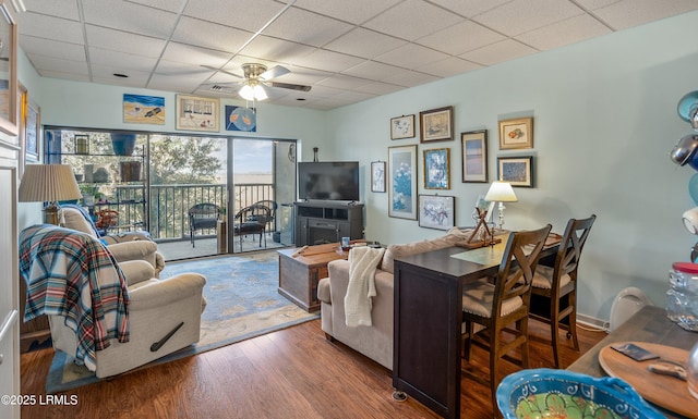 living room featuring dark hardwood / wood-style floors, a drop ceiling, and ceiling fan