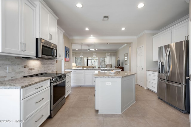 kitchen featuring a peninsula, ornamental molding, appliances with stainless steel finishes, white cabinetry, and tasteful backsplash