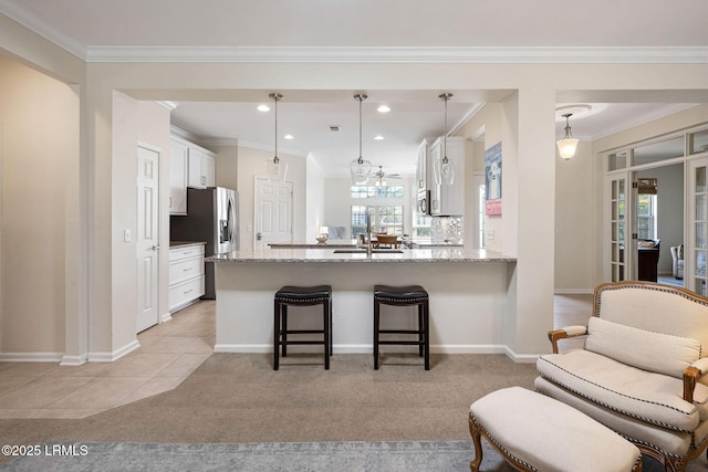 kitchen featuring light colored carpet, light stone counters, a peninsula, a kitchen breakfast bar, and white cabinetry