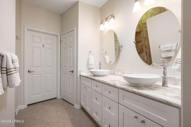 full bath with tile patterned flooring, double vanity, baseboards, and a sink