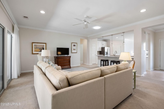 living room with ceiling fan, crown molding, baseboards, and light carpet