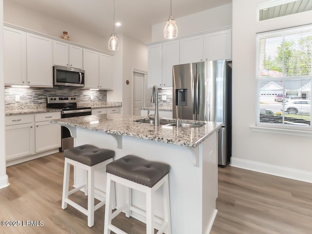 1872 Hearthstone Lake Dr, Ridgeland, SC 29936 - kitchen with stainless steel appliances, decorative backsplash, light wood-type flooring, white cabinets, and a sink