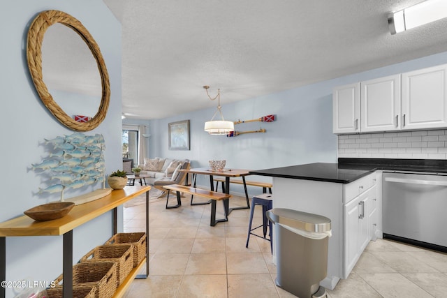 kitchen featuring light tile patterned flooring, decorative light fixtures, dishwasher, white cabinets, and backsplash