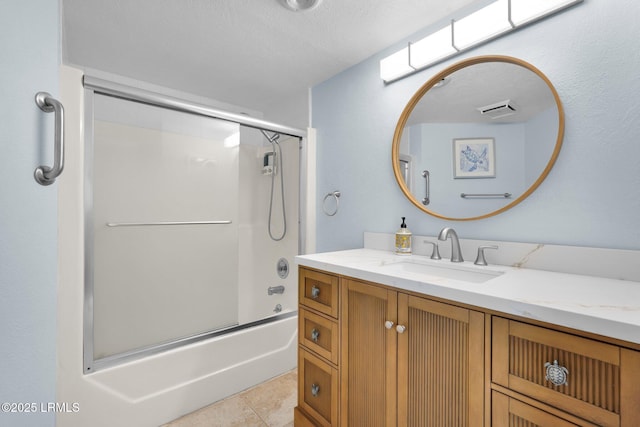 bathroom featuring vanity, a textured ceiling, tile patterned floors, and combined bath / shower with glass door