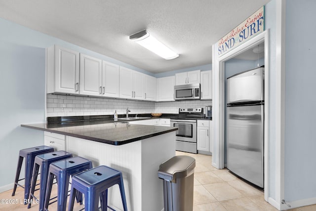 kitchen with white cabinetry, kitchen peninsula, and appliances with stainless steel finishes