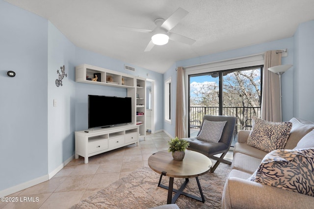 living room with ceiling fan, a textured ceiling, and light tile patterned flooring