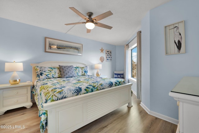 bedroom with ceiling fan, wood-type flooring, and a textured ceiling