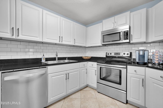 kitchen featuring sink, light tile patterned floors, appliances with stainless steel finishes, tasteful backsplash, and white cabinets