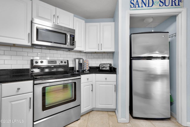 kitchen with light tile patterned flooring, appliances with stainless steel finishes, white cabinets, and backsplash