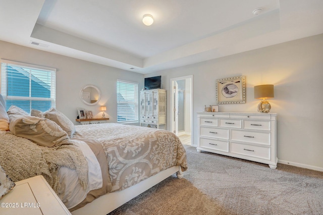 bedroom with light carpet, multiple windows, visible vents, and a raised ceiling