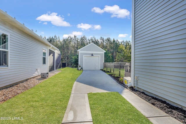 view of yard with driveway, a garage, fence, and an outdoor structure