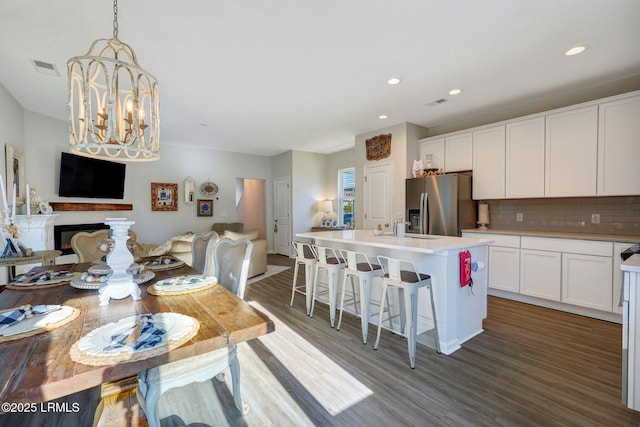 kitchen with backsplash, stainless steel refrigerator with ice dispenser, open floor plan, and wood finished floors