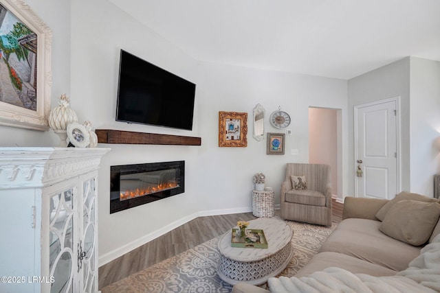 living room with a glass covered fireplace, baseboards, and wood finished floors