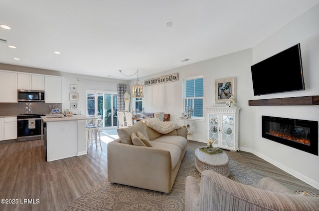 living area with recessed lighting, wood finished floors, visible vents, baseboards, and a glass covered fireplace
