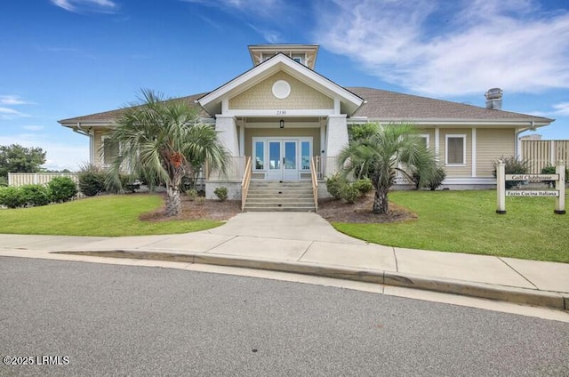 view of front of property with a front yard, french doors, and a chimney